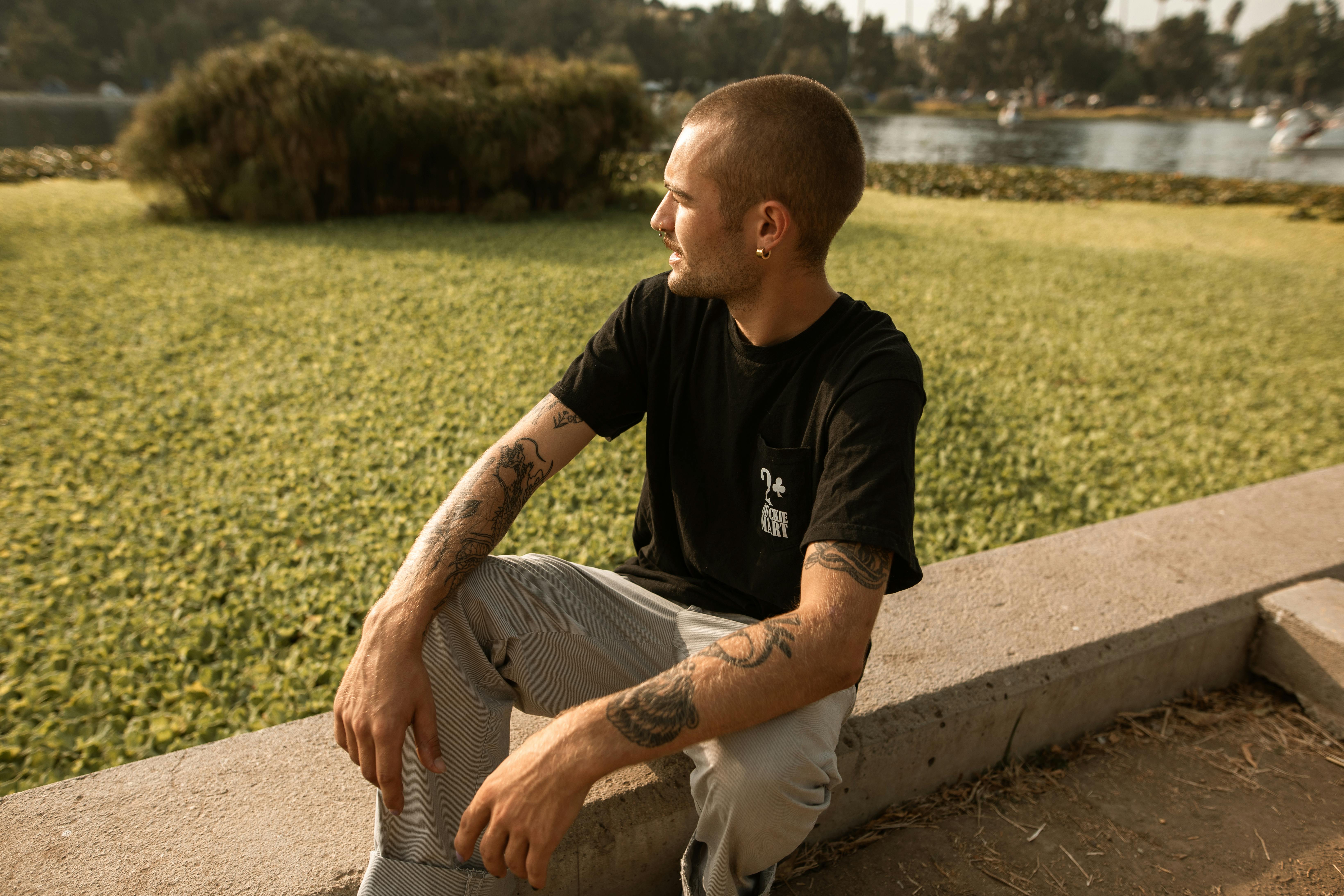 man in black crew neck t shirt sitting on concrete bench