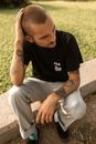 Man in Black Crew Neck T-shirt and Gray Pants Sitting on Brown Concrete Bench during