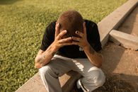 Man in Black T-shirt and White Pants Sitting on Brown Concrete Bench