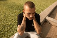 Man in Black Crew Neck T-shirt and White Shorts Sitting on Concrete Bench