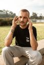 Man in Black Crew Neck T-shirt and White Pants Sitting on Brown Concrete Bench during