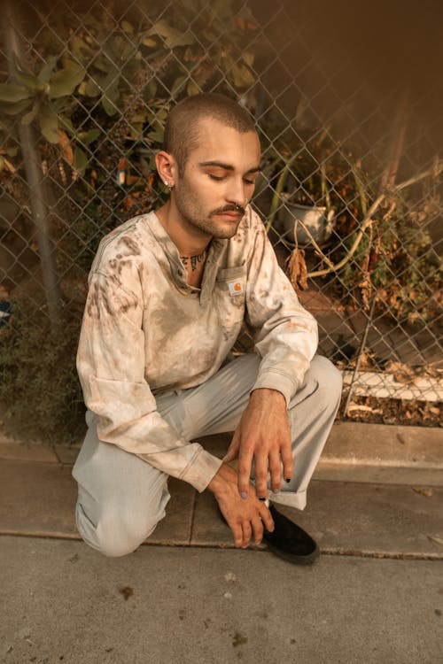 Free Man Kneeling on a Sidewalk Stock Photo