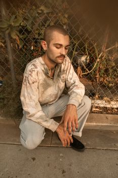 一位留着胡须的男子坐在户外栅栏旁，沉思着，捕捉着沉思的情绪
