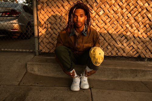 Man in Brown Jacket and Brown Pants Sitting on Gray Concrete Floor