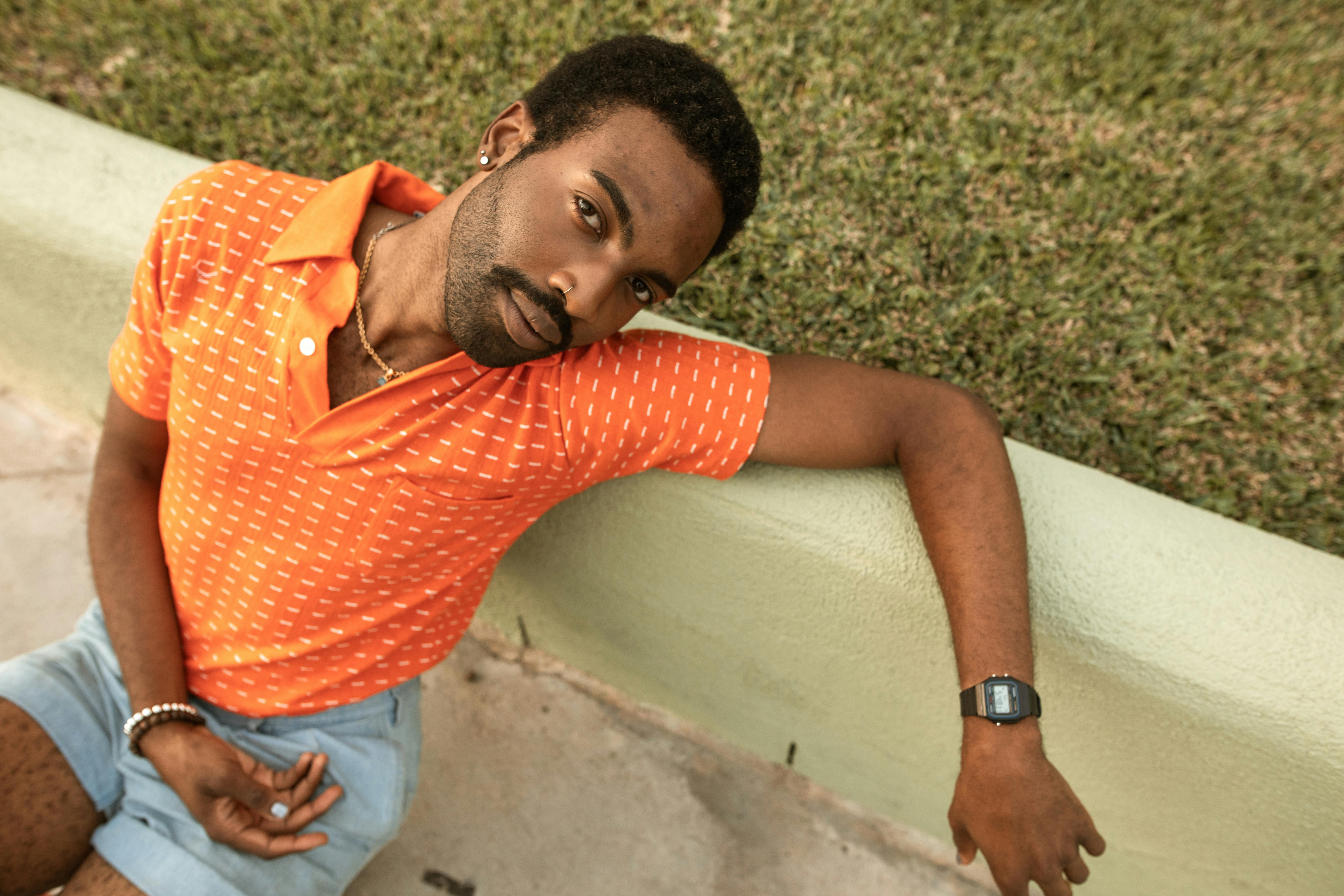 a man in orange polo shirt sitting on concrete bench