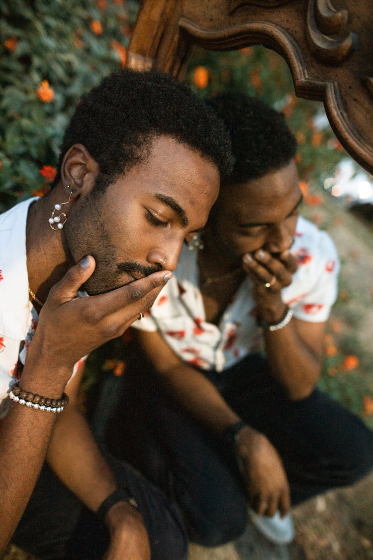 A Man Covering His Mouth While Leaning On A Mirror