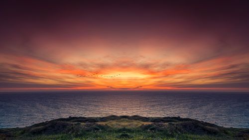 Free A breathtaking sunset over a calm ocean, with a vivid orange sky creating a serene atmosphere. Stock Photo