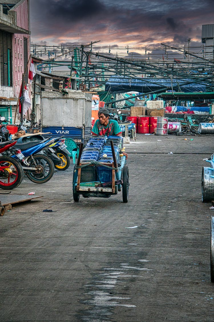 A Man Pushing A Cart With Containers