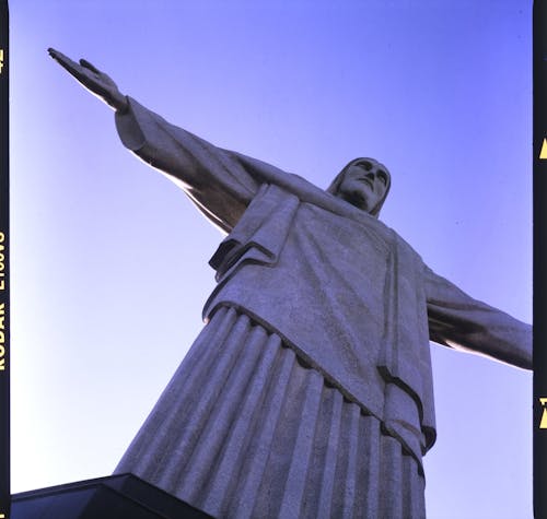 Picture of huge statue of Jesus Christ with arms spread under blue sky in Rio de Janeiro