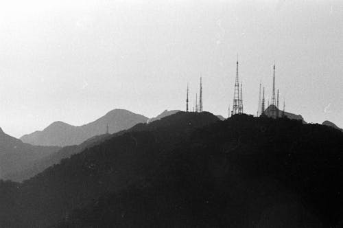 Monochrome vintage photo of tall power line tower on top of black mountain ridge