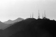 Monochrome vintage photo of tall power line tower on top of black mountain ridge