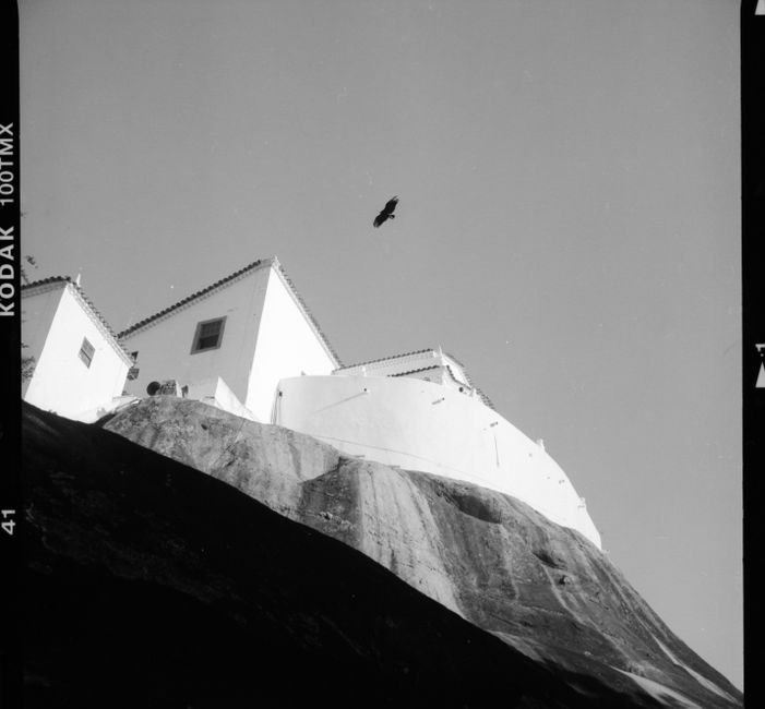 Film shot of white stone building placed on edge of high hill in sunlight