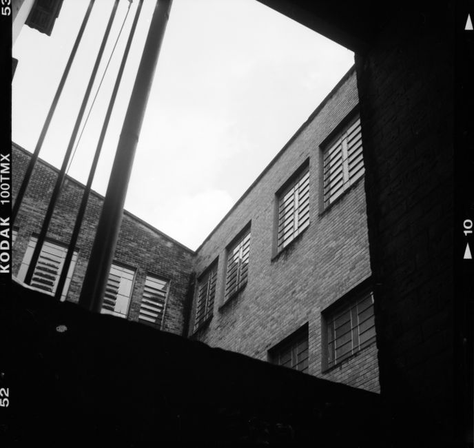Black and white photo of exterior brick wall of house through opened window