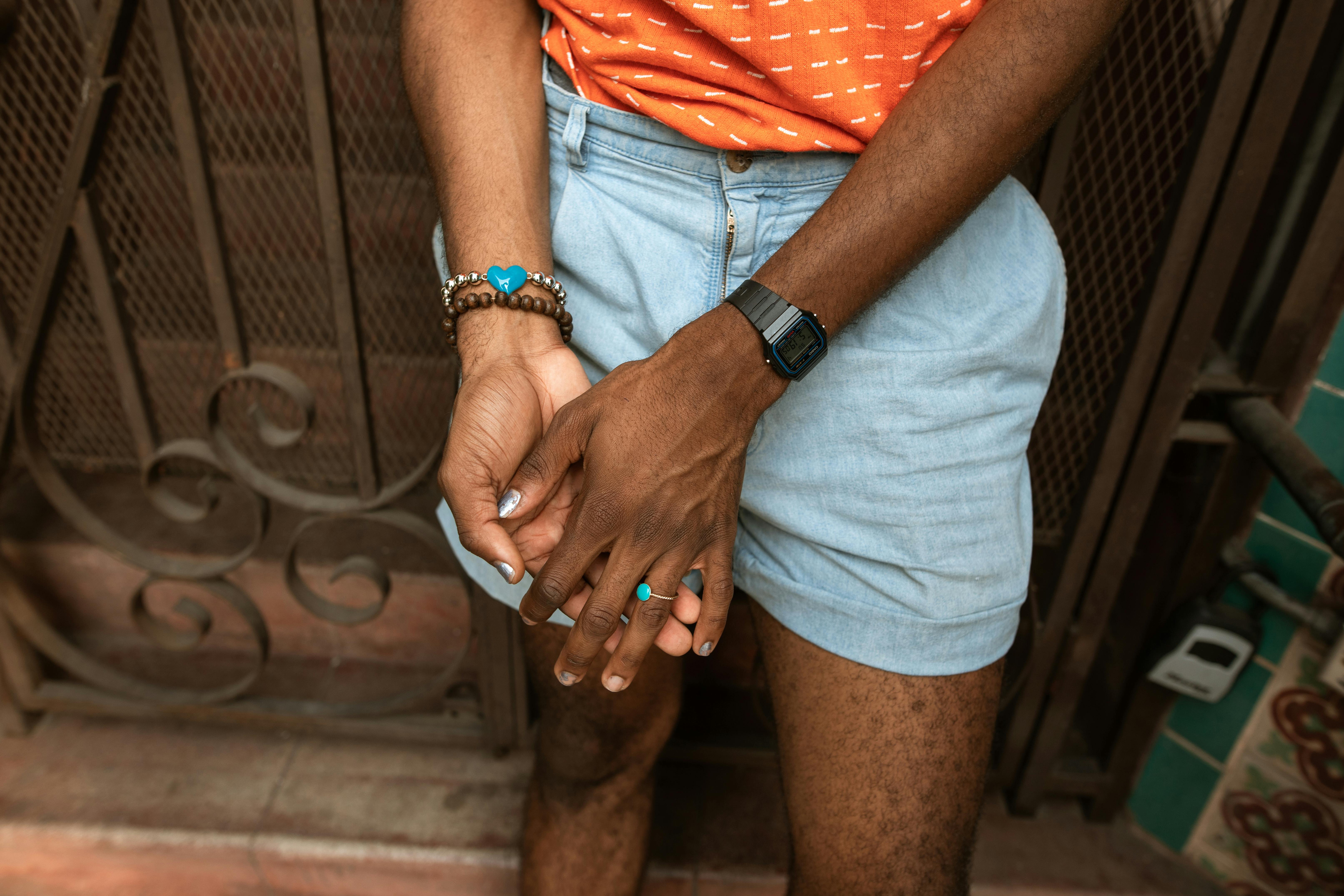 Stylish adult with bracelets and rings posing casually outdoors in summer.