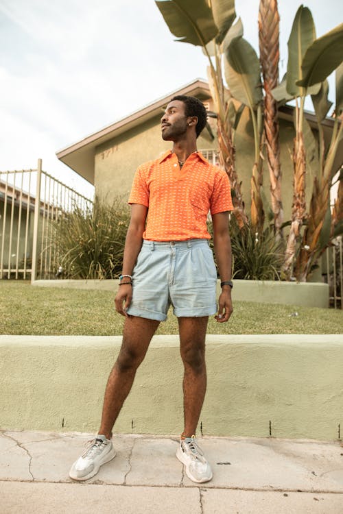 Free Man in Orange Shirt and Blue Denim Shorts Stock Photo