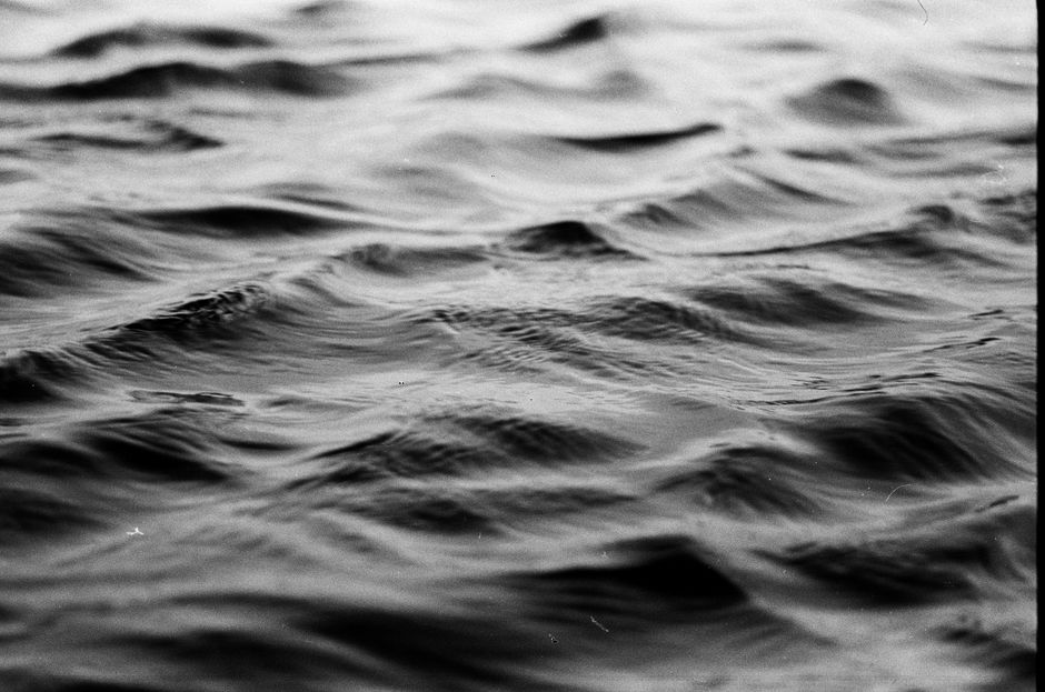 Black and white background of flowing ripple of ocean wave in full frame