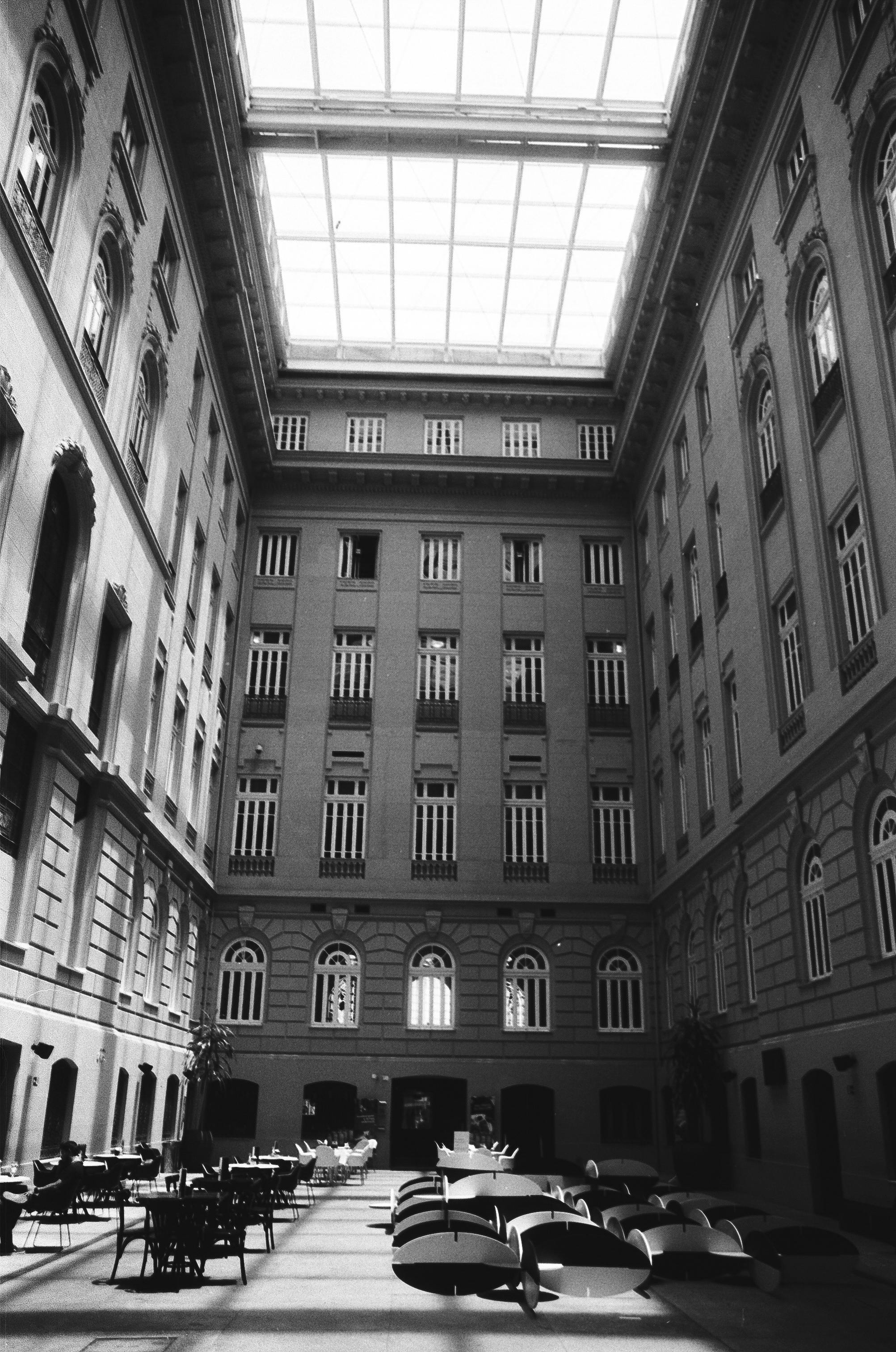 Black and white inner patio with tables and chairs among walls of old classic building