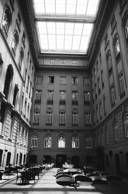 Black and white inner patio with tables and chairs among walls of old classic building