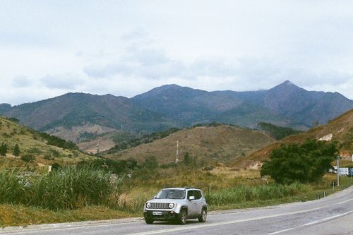 Free A car driving on a road with majestic mountains in the background, perfect for travel theme. Stock Photo