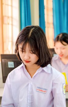 Two students concentrating on their studies in a classroom setting with computers and a soft focus background.