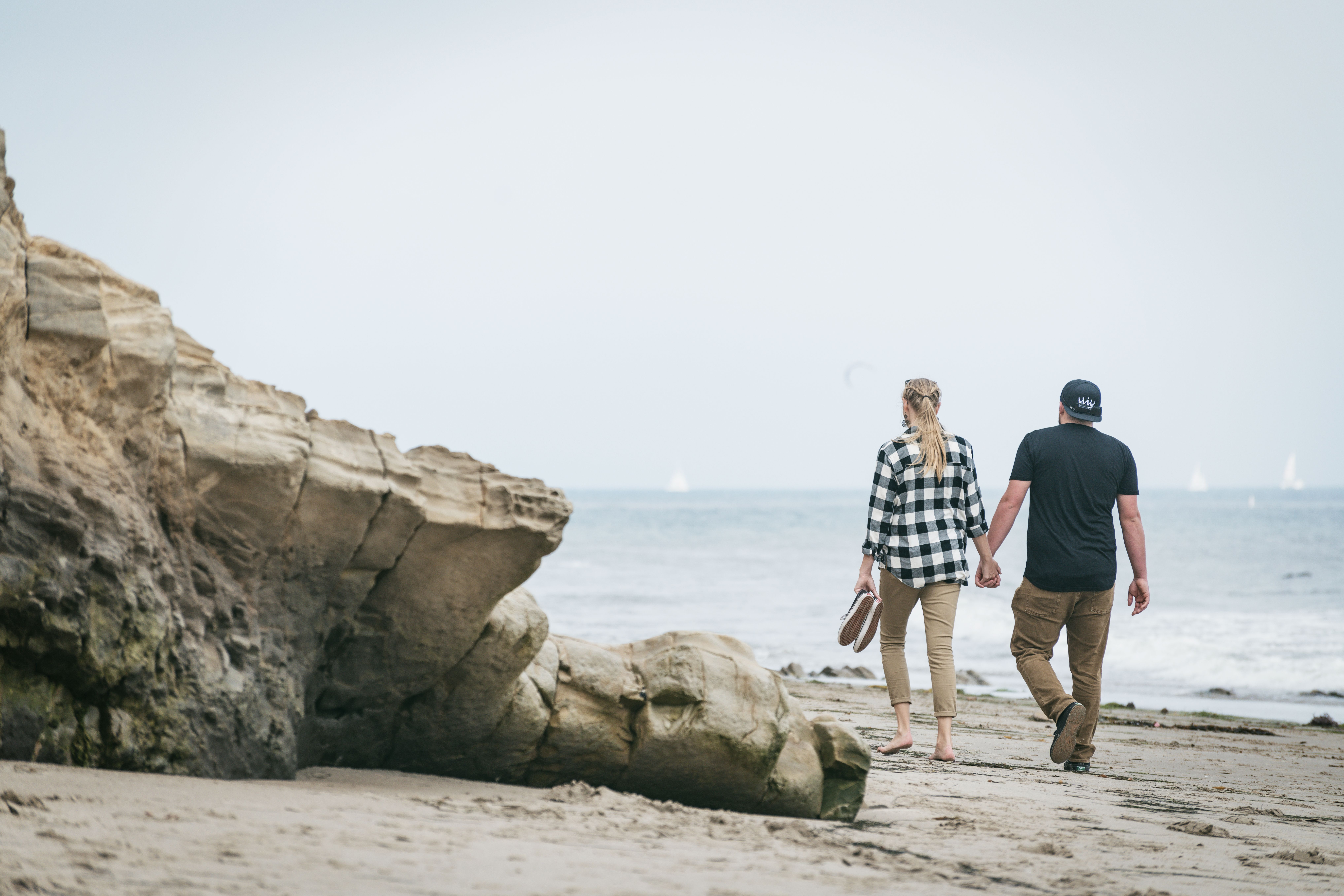 A couple holding hands and walking along a coastal beach in Santa Barbara, CA. - Santa Bárbara