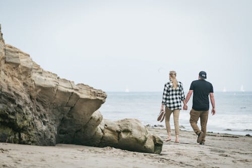 Man and Woman Standing on Brown Sand near the Beach