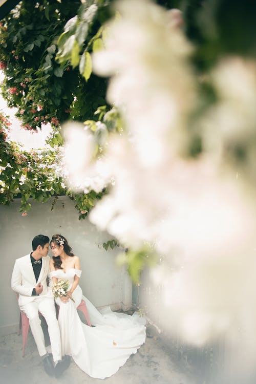 Newlywed couple sharing an intimate moment under a floral archway in a lush garden setting.