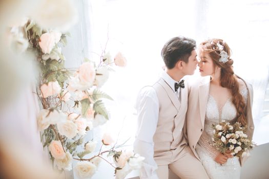 Elegant couple sharing a tender moment with floral backdrop at their wedding.
