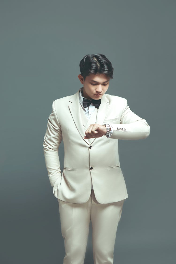 A Man In A White Suit Checking His Watch