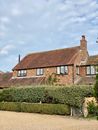 Brown Brick House Near Green Grass Field Under White Clouds