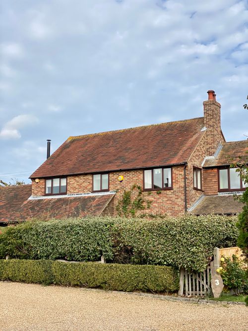 Free Red brick house with a hedge and fence in West Sussex, England. Stock Photo