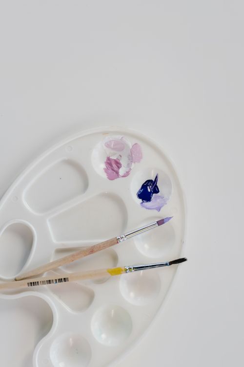 Free Close-up of an art palette with paintbrushes and vibrant colors on a white background. Stock Photo