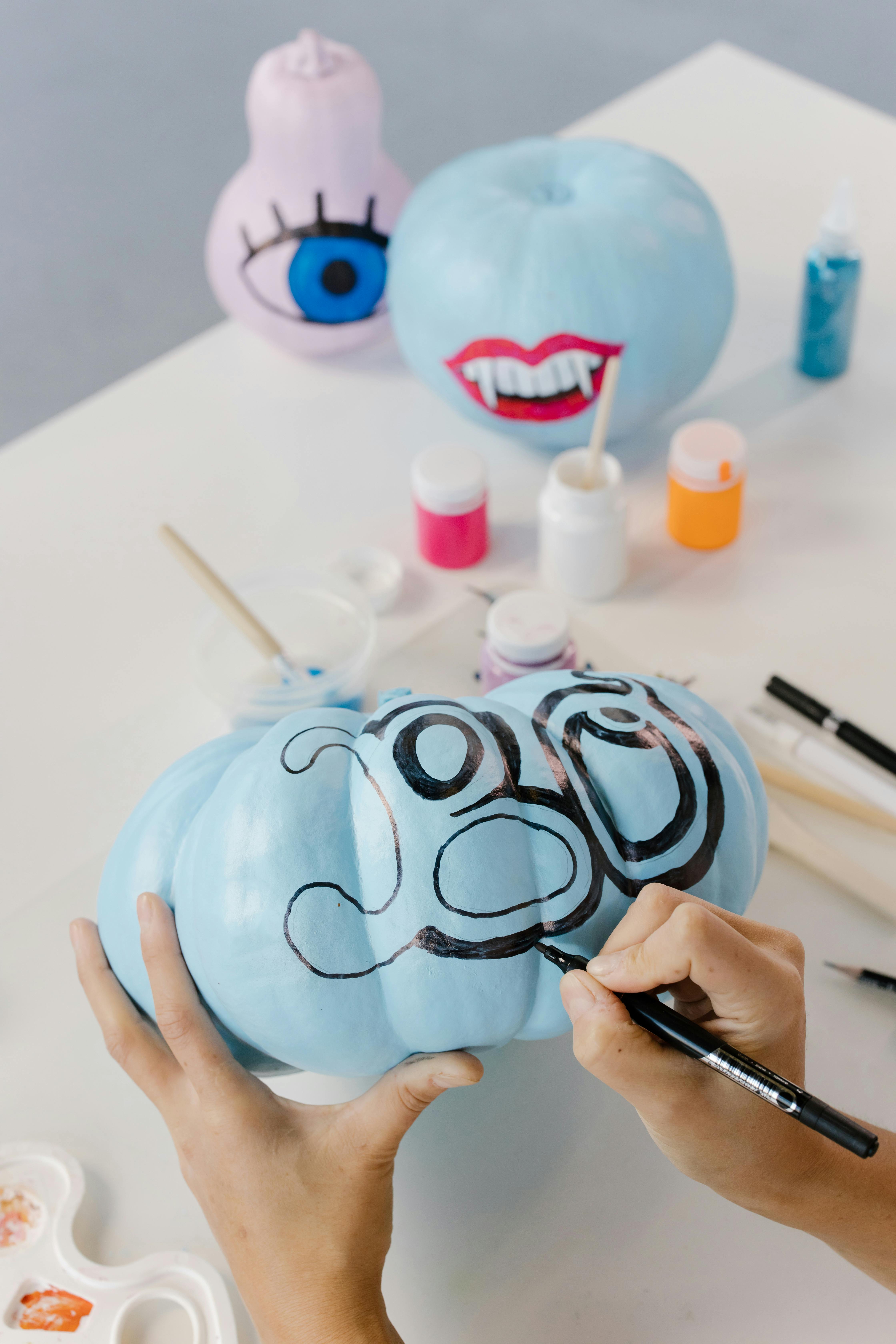 person writing on a blue pumpkin