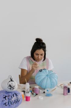 一名妇女用色彩缤纷的艺术图案绘制南瓜，以装饰万圣节