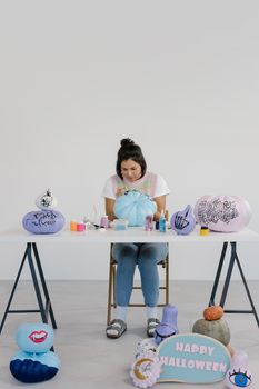 一名妇女在白色背景上用艺术用品画万圣节南瓜