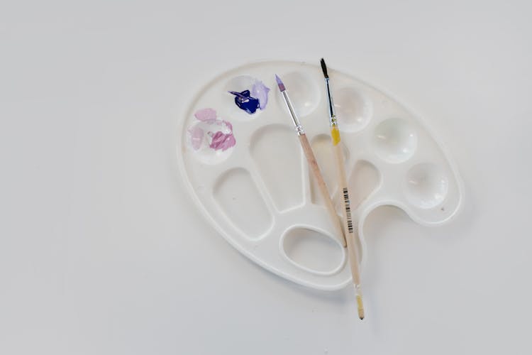 A Palette With Paint On A White Surface