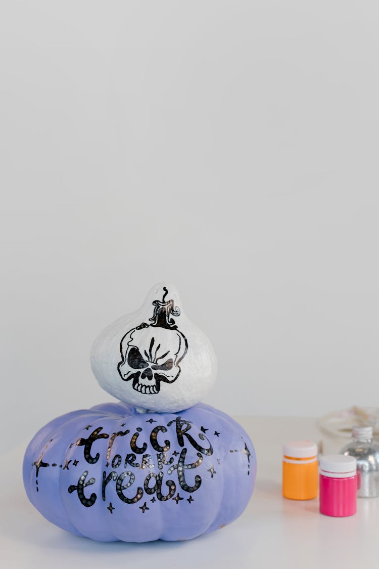 Pumpkin Painted Purple With Skull Design On A White Surface