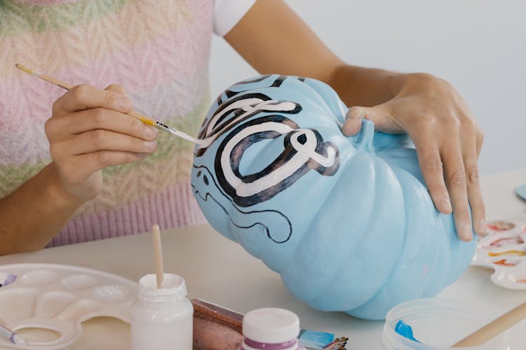 Person Holding A Paint Brush Painting The Pumpkin 