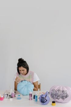 一名妇女在室内绘制南瓜，为万圣节做创意装饰