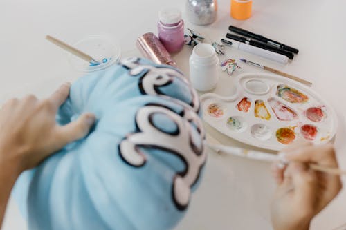 A Close-Up Shot of a Person Painting a Pumpkin