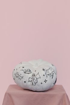 白色南瓜上绘有万圣节图画，置于柔软的粉红色背景之上，非常适合节日装饰