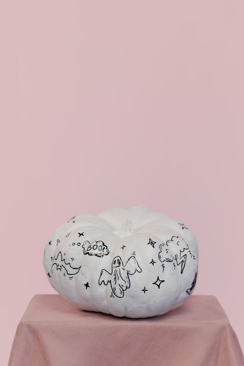 Free White pumpkin with Halloween drawings on a soft pink backdrop, perfect for holiday decor. Stock Photo