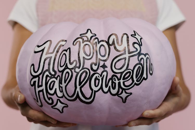 A Woman Holding A Painted Pumpkin