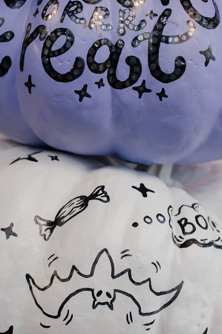 Close-up Photo Of Purple And White Pumpkins With Scary Drawings