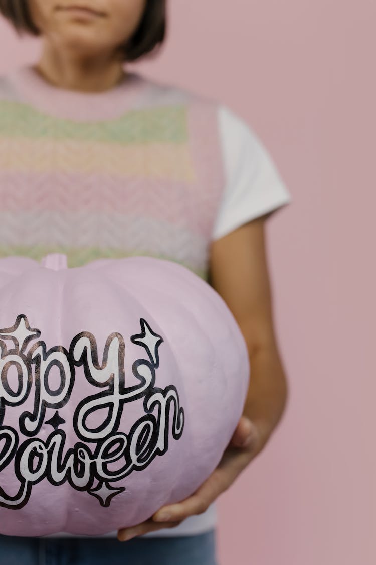 
A Woman Holding A Painted Pumpkin