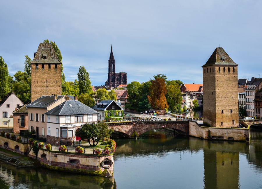 A scenic view of Strasbourg featuring Ponts Couverts and the cathedral in the background.