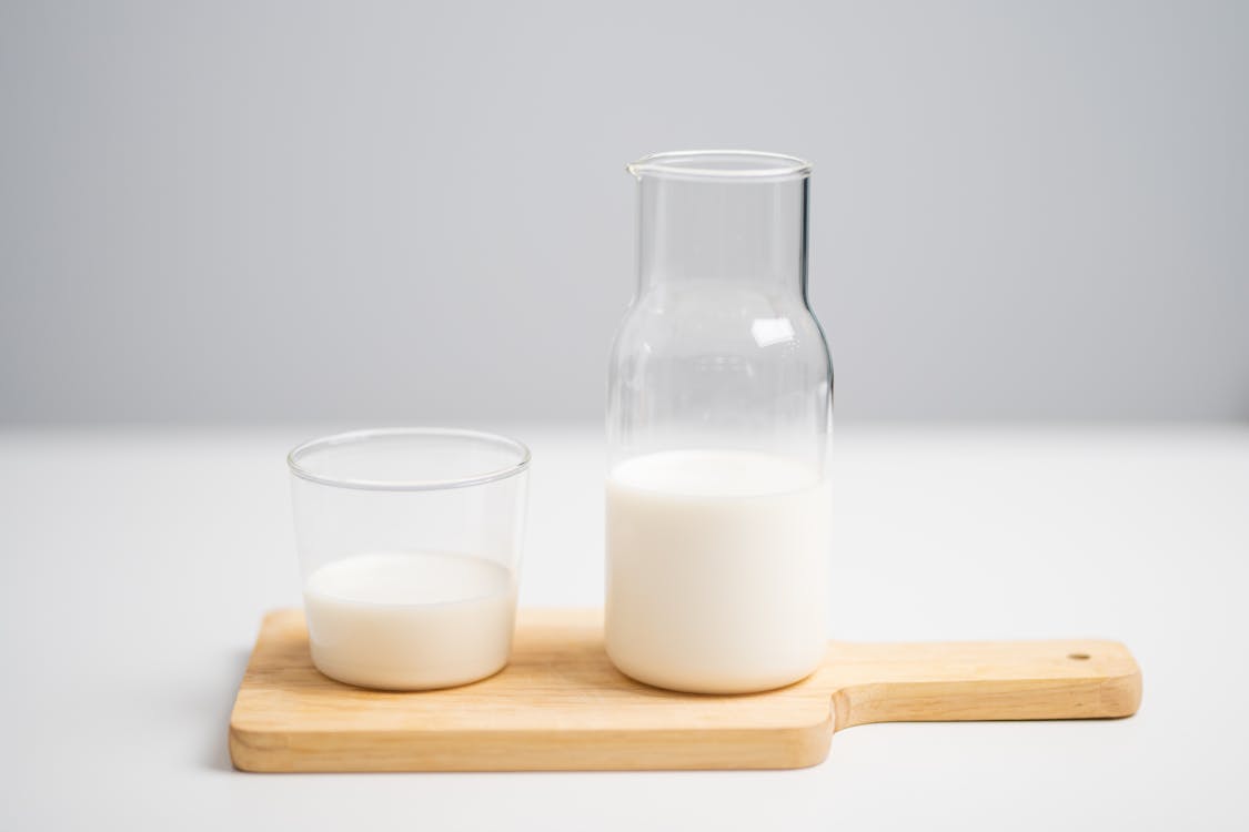 Free Milk in Pitcher and Glass Placed on Wooden Chopping Board Stock Photo
