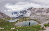 宁静的高山湖畔，一个孤独的人站在群山缭绕之中