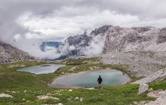 宁静的高山湖畔，一个孤独的人站在群山缭绕之中
