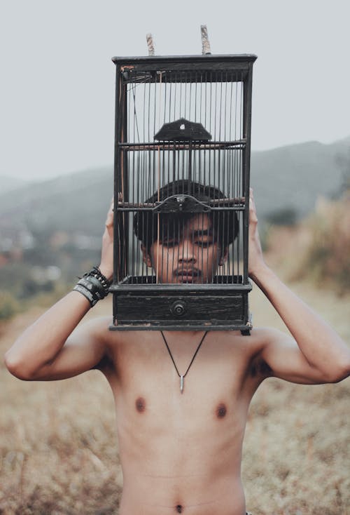 Shirtless ethnic man with cage on head behind mounts
